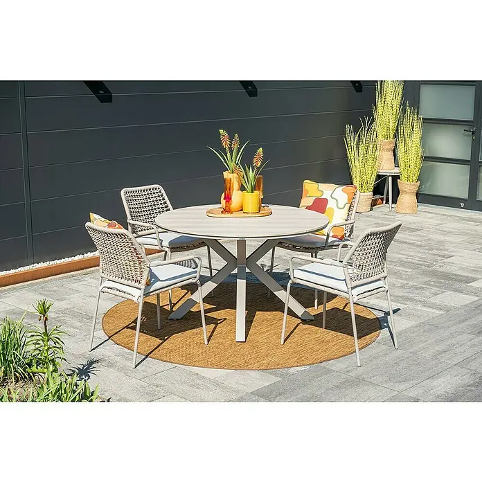 Garden Impressions Gartentisch rund Edison - Ø x H: 122 x 75 cm, Aluminium, Vironwood, Taupe - Runder Outdoor-Esstisch und vier Korbstühle mit Kissen auf einer Terrasse. Das hellgraue Set steht auf einem runden Flechtteppich.