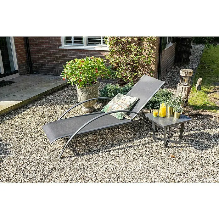 Garden Impressions Gartenliege - B x T x H: 70 x 203 x 28 cm, Aluminium, Schwarz/Anthrazit - Dunkelgraue Chaiselongue und passender Beistelltisch auf Kies, bereit für entspannte Stunden im Freien mit Getränken.