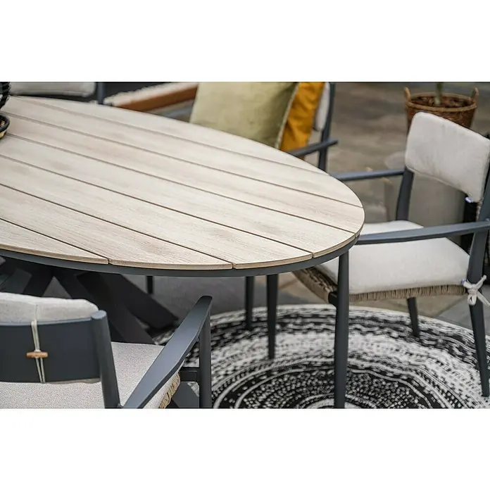 Garden Impressions Gartentisch Edison - L x B x H: 220 x 115 x 75 cm, Aluminium, Vironwood, Oval, Schwarz/Braun - Ovale Outdoor-Esstischgarnitur: Tisch mit hellen Holzlamellen und dunklem Gestell, Stühle mit beigen Kissen auf einem gemusterten Teppich.