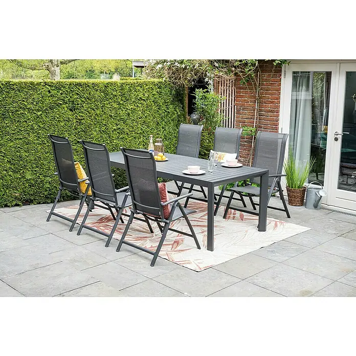 Garden Impressions Garten-Positionssessel Limone - Aluminium, Klappbar, Schwarz/Anthrazit, B x T x H: 71,5 x 60 x 110 cm - Graues Outdoor-Essgruppe mit Lattenrosttisch und sechs Netzstühlen auf einem gemusterten Teppich auf einer Terrasse.
