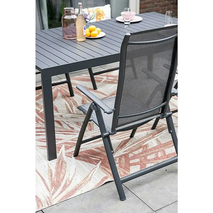 Garden Impressions Garten-Positionssessel Limone - Aluminium, Klappbar, Schwarz/Anthrazit, B x T x H: 71,5 x 60 x 110 cm - Dunkelgrauer Gartentisch und Klappstuhl mit Netzgewebe, auf einem gemusterten Teppich auf der Terrasse.