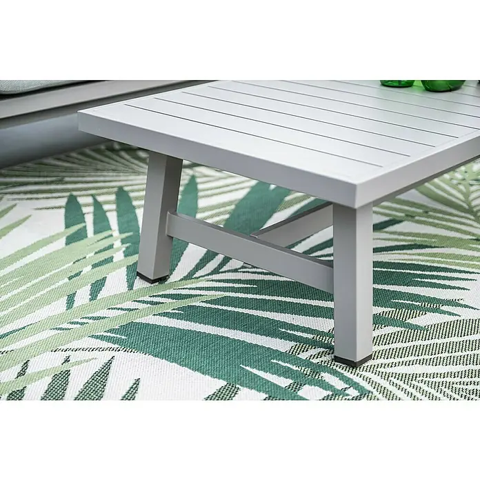 Garden Impressions Loungemöbel-Set Monti - 4 -tlg., Aluminium, Beige - Grauer Metall-Couchtisch für den Außenbereich mit Lattenrostplatte, auf einem grünen Palmenblattmusterteppich.