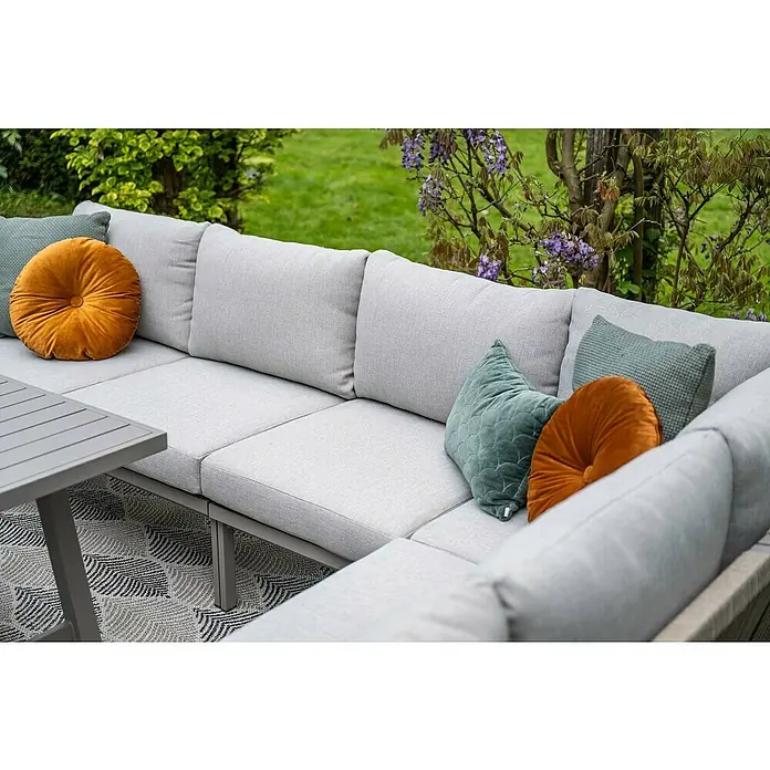 Garden Impressions Loungemöbel-Set Monti - 5 -tlg., Aluminium, Polyester, Grau - Helles graues Outdoor-Lounge-Set mit orangefarbenen und grünen Kissen und einem kleinen grauen Tisch auf einem gemusterten Teppich im Garten.