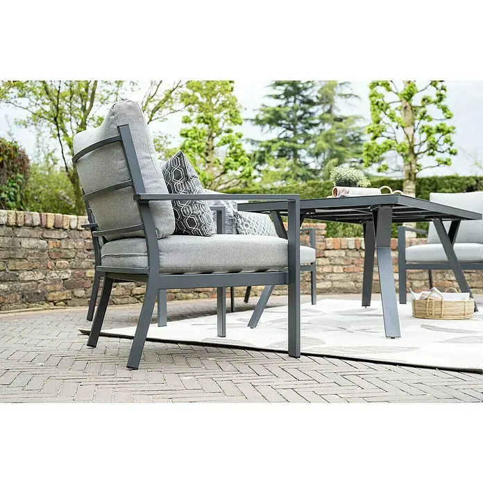 Garden Impressions Loungemöbel-Set Sergio -  - Graue Metall-Gartenstühle mit passenden Kissen und gemusterten Akzentkissen um einen grauen Tisch auf einer gepflasterten Terrasse.