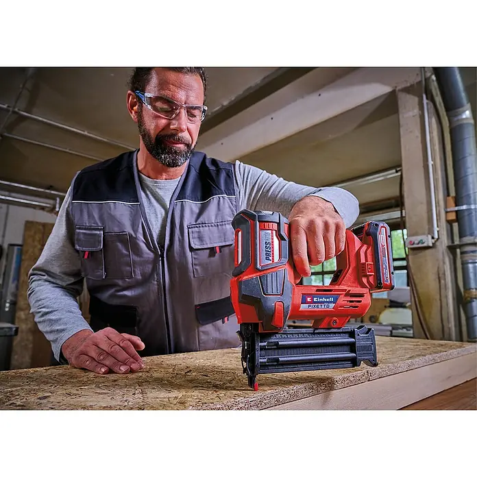 Einhell Professional PXC 18V Akku-Nagler Fixetto 18/50 N - 18 V, Ohne Akku, Länge Nagel: 15 mm - 50 mm - Ein Handwerker mit einer Einhell Akku-Nagelpistole PRESSITO 18/19 im Einsatz. Das Gerät ist rot und schwarz und wird zum Befestigen von Werkstücken verwendet.