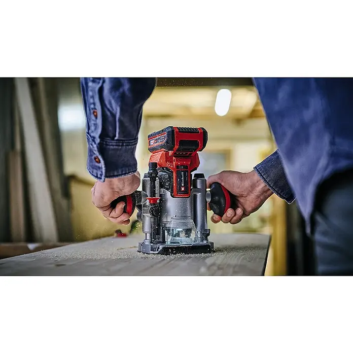 Einhell Professional Power X-Change 18V Akku-Kombifräse TP-RO 18 Set Li BL - Solo - 18 V, Ohne Akku, 40 mm - Ein Mann verwendet eine Einhell Akku-Oberfräse auf einem Holzbrett, um präzise Kantenbearbeitungen durchzuführen. Das Gerät ist rot und schwarz.