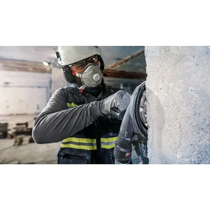 Bosch Expert Diamant-Topfscheibe for Concrete - Durchmesser Scheibe: 125 mm, Höhe Segment: 5 mm, Bohrung: 22,23 mm - Bauarbeiter mit Schutzmaske, Brille und Helm schleift eine Betonwand mit einem Betonschleifer. Für sicheres und staubfreies Arbeiten.