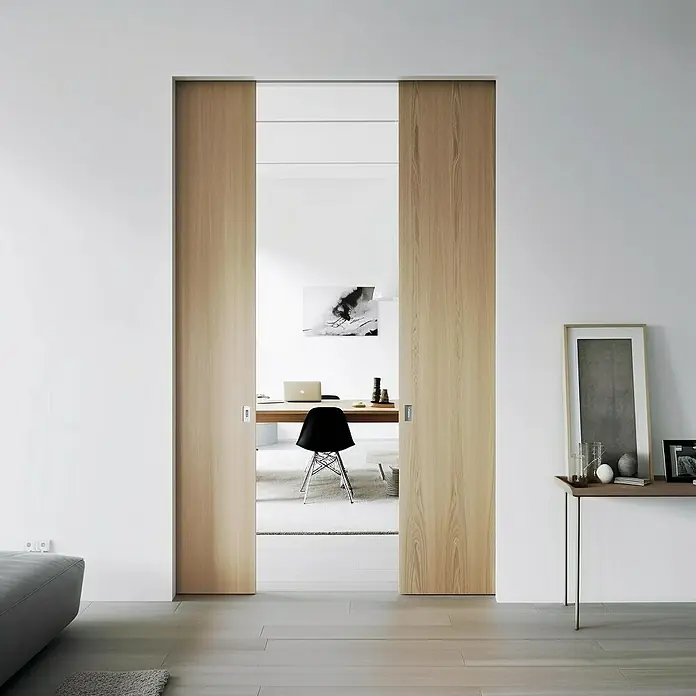Entravia Gipskartonlaibung CW100/150 - Holzschiebetüren, 2-flügelig, Passend für: Entravia Simple-Pocket Schiebetürsystem - Helle Holzschiebetüren öffnen den Blick auf ein modernes Büro. Die Türen fügen sich nahtlos in das minimalistische Design des Raumes ein.