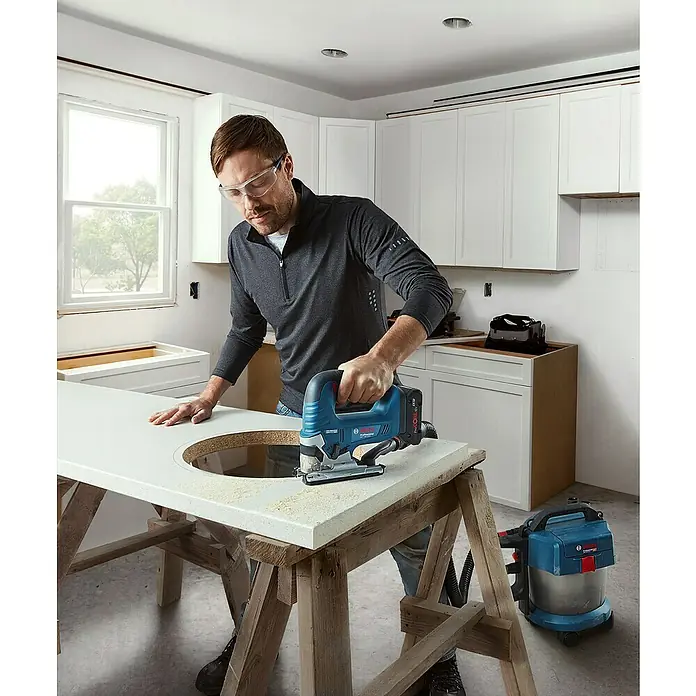 Bosch Professional AMPShare 18V Akku-Pendelhubstichsäge GST 18V-125 B - 18 V, Ohne Akku, Leerlaufhubzahl: 0 /min - 3.500 /min - Ein Handwerker verwendet eine Bosch Stichsäge, um ein Loch in eine Arbeitsplatte einzuschneiden. Sicherheit geht vor mit Schutzbrille!