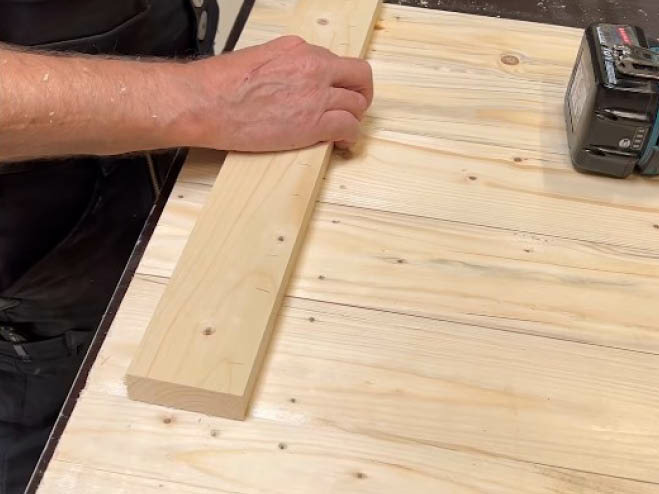 Eine Querstrebe wird auf mehrere Holzlatten gelegt und miteinander verschraubt