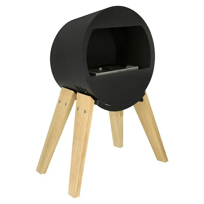 Aduro Bioethanol-Kamin B2 - 46 x 63 x 70 cm, Schwarz - Abgebildet ist ein moderner, schwarzer Kaminofen auf hellen Holzbeinen. Der Ofen hat eine offene Brennkammer und ein minimalistisches Design.