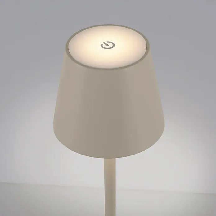 Just Light Lámpara de sobremesa a batería Euria - 3 W, L x An x Al: 11 x 11 x 37 cm, Blanco cálido, Gris - Primer plano de una lámpara de mesa moderna color crema con un símbolo de encendido iluminado en la parte superior.