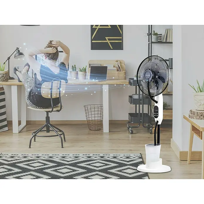 Purline Misty Ventilador de pie 4 - Negro, 40 cm, 125 cm - Un ventilador de pie Purline proporciona una brisa fresca en un espacio de trabajo moderno con una persona en el escritorio.