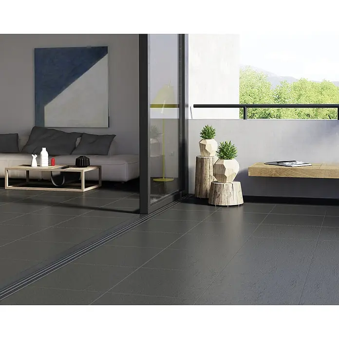 Granulati Zandobbio Terrassenfliese Slate Black - 60 x 60 x 2 cm, Schwarz, Matt - Ein modernes Wohnzimmer mit grauen Bodenfliesen, die sich bis auf einen Balkon erstrecken, und einer Schiebetür, die den Innen- und Außenbereich verbindet.