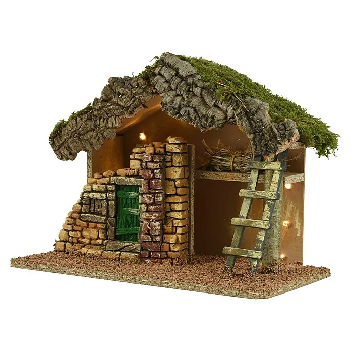 LED-Krippe Naturel - 32 x 17 x 24 cm, Anzahl Leuchtmittel: 10 Stk. - Detailaufnahme einer Krippenszene, die ein rustikales Haus mit Steindetails, grüner Tür und einer Leiter zeigt, beleuchtet von warmem Licht.