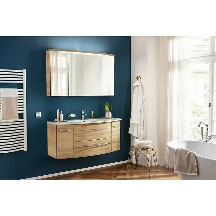 Camargue Badmöbel-Set - Berg Eiche, Matt, 120 cm, 3 -tlg., 21,6 W - Elegantes Badezimmer-Interieur mit einem Waschtischunterschrank in Holzoptik, einem Spiegelschrank und einem weißen Heizkörper.
