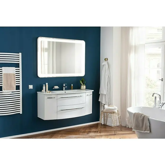 Camargue Swing K Waschtischunterschrank - B x T x H: 119 x 45,9 x 51,8 cm, Weiß, Farbe Griff: Chrom - Elegantes Badezimmer mit einem beleuchteten Spiegel über einem weißen Waschtisch mit Schubladen und einem Handtuchwärmer an der Wand.
