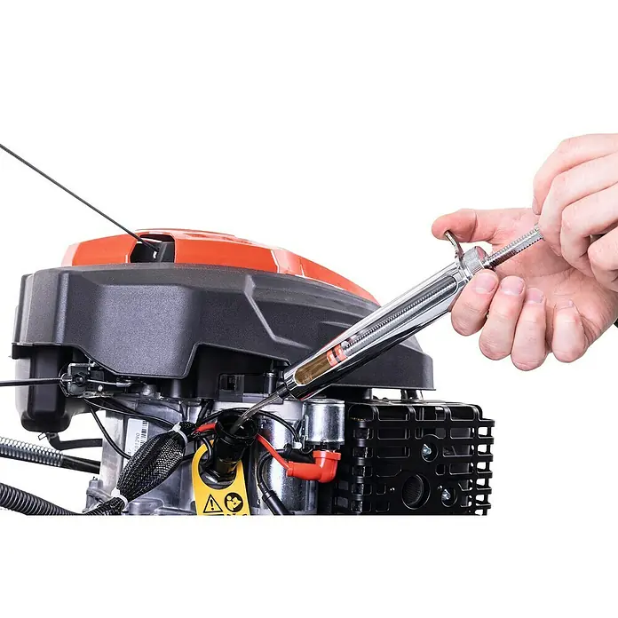 Scheppach Wartungs-Kit für Rasenmäher - 4-Takt-Benzin Geräte, 5 -tlg. - Ein Bild zeigt einen Mann, der mit einer Ölspritze Öl in einen Motor einspritzt. Werkzeug und Motor sind gut sichtbar.