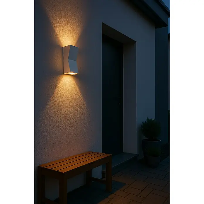 Forlight Aplique exterior LED Loyd - 4,1 W, 6,2 x 7,9 x 14 cm, Gris, IP55, 2 ud. - Primer plano de un moderno aplique de pared blanco que emite luz cálida, junto a una puerta oscura en la fachada de una casa.