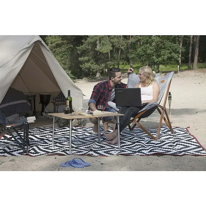 Bo-Camp Campingstuhl Bloomsbury - B x T x H: 75 x 87 x 96 cm, Grau/Braun, Holz/Polyestergewebe - Ein Paar entspannt beim Camping mit Laptop, Wein und Snacks auf einem stilvollen, schwarz-weiß gemusterten Außenteppich.