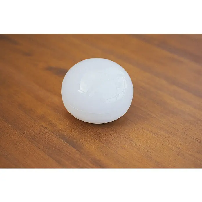 New Garden LED-Poolbeleuchtung Coco Floating Blulb - Durchmesser: 11 cm, Weiß, LED - Nahaufnahme einer weißen Kugel, die auf einer glatten Holzoberfläche liegt. Das Licht reflektiert sanft auf der Kugel.