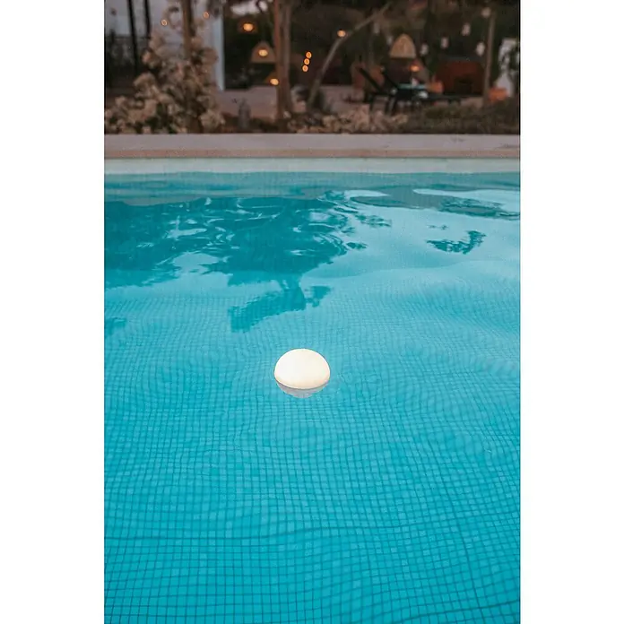 New Garden LED-Poolbeleuchtung Coco Floating Blulb - Durchmesser: 11 cm, Weiß, LED - Eine Nahaufnahme einer beleuchteten Poolleuchte, die im türkisfarbenen Wasser eines Pools schwimmt, mit einem verschwommenen Hintergrund.