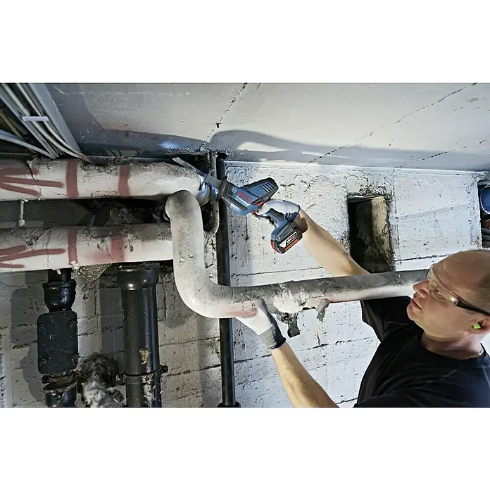 Bosch Professional AMPShare 18V Akku-Säbelsäge GSA 18 V-LI C L-Boxx18 V, Ohne Akku, 0 /min - 3.050 /min, Koffer - Ein Handwerker verwendet eine Bosch Säbelsäge, um ein Rohr zu schneiden. Das Werkzeug ist ideal für enge Räume und vielseitige Anwendungen.