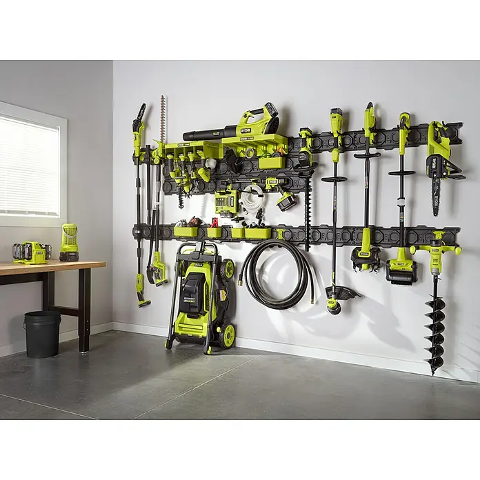 Ryobi Link Systemregal RSLW818 - 372 x 95 x 77 mm, Traglast: 6,8 kg - Eine Wand mit dem Ryobi Link Aufbewahrungssystem, an dem verschiedene Gartengeräte wie Rasenmäher und Heckenscheren hängen.
