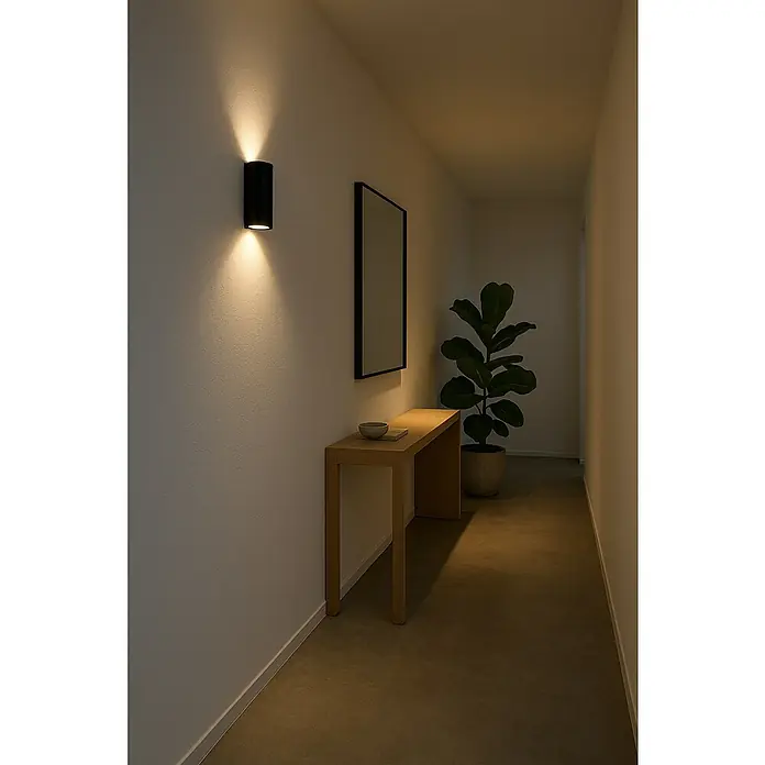 Philips Aplique exterior Nightingale - 35 W, 9,6 x 8 x 16 cm, IP44 - Pasillo con un aplique negro, un espejo sobre una consola y una planta de interior.