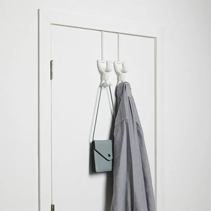 Umbra Türgarderobe Buddy - L x B x H: 22 x 6 x 32 cm, Anzahl Haken: 2 Stk., Weiß - Eine weiße Türgarderobe mit zwei Figuren, die an der Stange hängen. Eine graue Jacke und eine blaue Handtasche hängen daran.