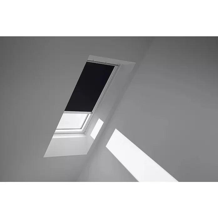 Velux Dachfensterrollo DSL S08 3009KWL - Farbe: Schwarz - 3009KWL, Farbe Schiene: Weiß, Solarbetrieben - Ein Dachfenster mit Verdunkelungsrollo in einem hellen Raum, das Licht und Schatten auf die Wand wirft.