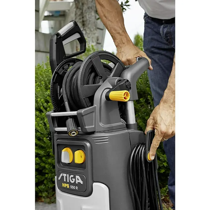 Stiga Hochdruckreiniger HPS 550 R - 2.500 W - Nahaufnahme des STIGA HPS 550 R Hochdruckreinigers mit Schlauchtrommel und Kabelaufwicklung, bedient von einer Person.