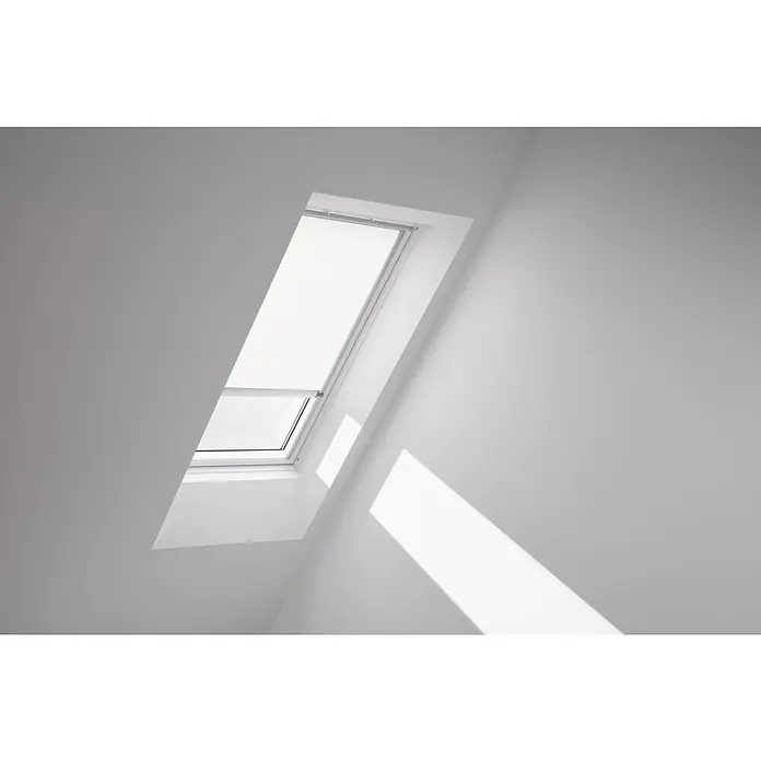 Velux Dachfensterrollo RSL SK08 1028K - Farbe: Weiß - 1028K, Farbe Schiene: Aluminium, Solarbetrieben - Dachfenster mit weißem Rollo in einem hellen Raum, das Sonnenlicht hereinlässt. Das Rollo ist teilweise heruntergelassen und sorgt für angenehme Lichtverhältnisse.