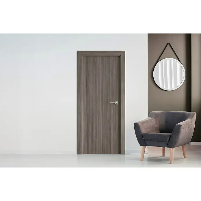Pack puerta de interior vinílica Boston - 62,5 x 203 cm, Izquierda - Elegante puerta de madera en un interior moderno, junto a un sillón y un espejo. La puerta impresiona por su elegancia sencilla.