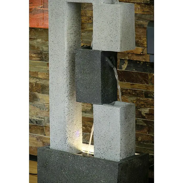 Dobar Gartenbrunnen - 40,5 x 21,5 x 90,5 cm, Kunststoff, Grau - Nahaufnahme eines modernen Zimmerbrunnens mit Wasserkaskade über verschiedenfarbige Steinblöcke, der eine ruhige Atmosphäre schafft.