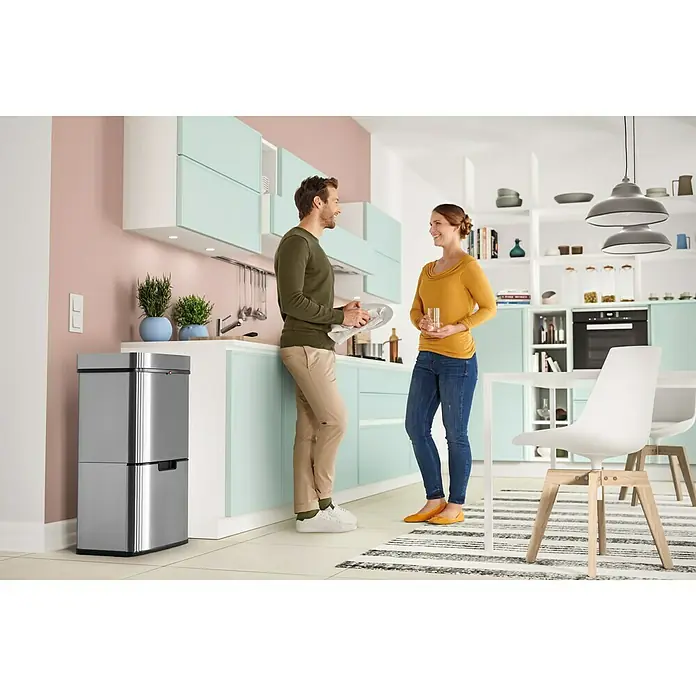 Hailo Mülltrennsystem Öko Vario XL - 54 l, Edelstahl, Edelstahl - Ein Paar unterhält sich in einer modernen Küche neben einem silbernen Abfalltrennsystem mit zwei Fächern.