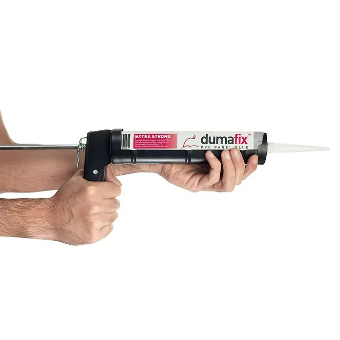 Adhesivo para moqueta y PVC - Apto para: Paneles de plástico, 310 ml - Primer plano de una pistola de calafateo con pegamento para paneles de PVC DUMAFIX sujeta por manos sobre un fondo negro.