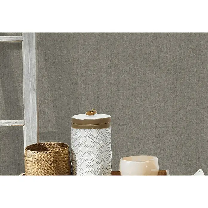 A.S. Création Hygge Vliestapete - Braun, Uni, 10,05 x 0,53 m - Nahaufnahme eines dekorierten Tischs mit einem gewebten Korb, einem weißen Keramikgefäß und einer kleinen Schale.