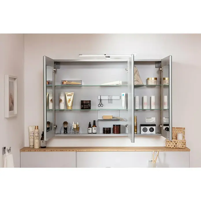 Fackelmann B.brillant LED-Spiegelschrank - B x H: 100 x 68 cm, 3-türig, Ast Eiche - Ein offener Spiegelschrank im Badezimmer mit diversen Kosmetikprodukten, die auf Glasböden ordentlich präsentiert werden. Helle Beleuchtung betont die klaren Linien.