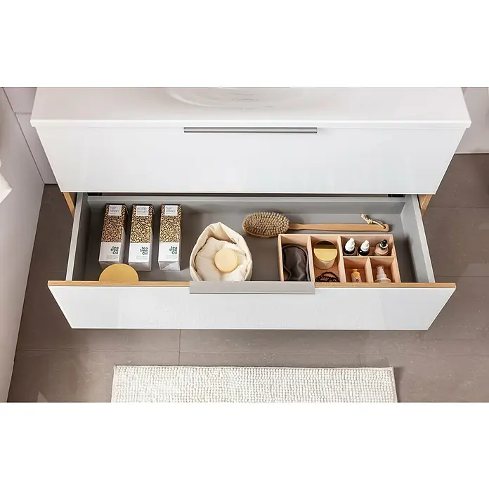 Fackelmann B.brillant Badmöbel-Set - Gesamtbreite Badmöbel: 100 cm, Weiß, Waschbecken aus Glas - Ein offener Badezimmerschrank mit diversen Beautyprodukten wie Ölen, Bürsten und Hautpflegeartikeln, die ordentlich verstaut sind.