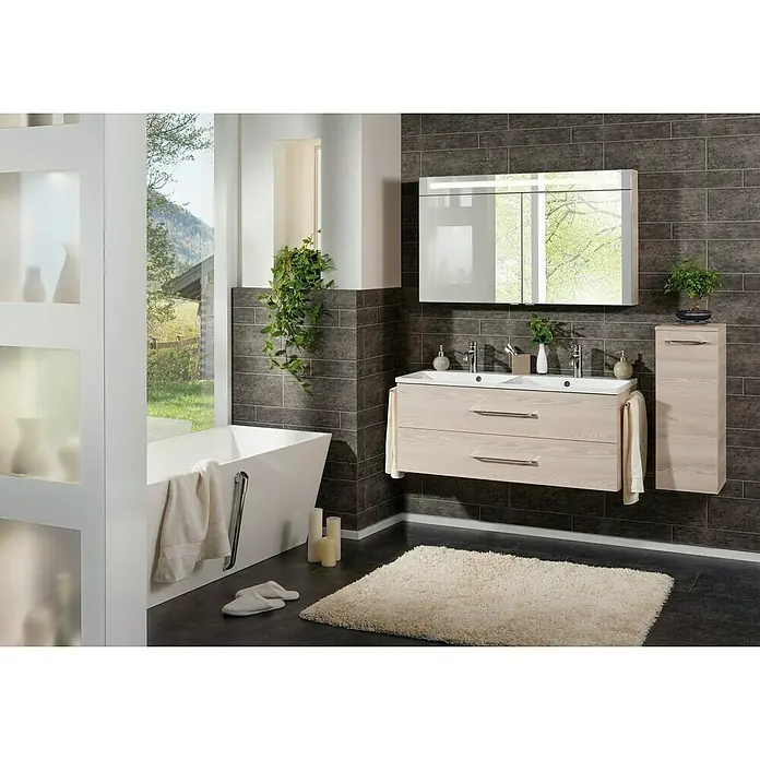 Fackelmann B.clever Badmöbel-Set - Gesamtbreite Badmöbel: 120 cm, Mit Doppel-Gussmarmorbecken, Alaska Esche Holzoptik, Matt - Ein helles Badezimmer mit einer Badewanne, einem Waschtisch mit zwei Schubladen und einem Spiegelschrank mit integrierter Beleuchtung.
