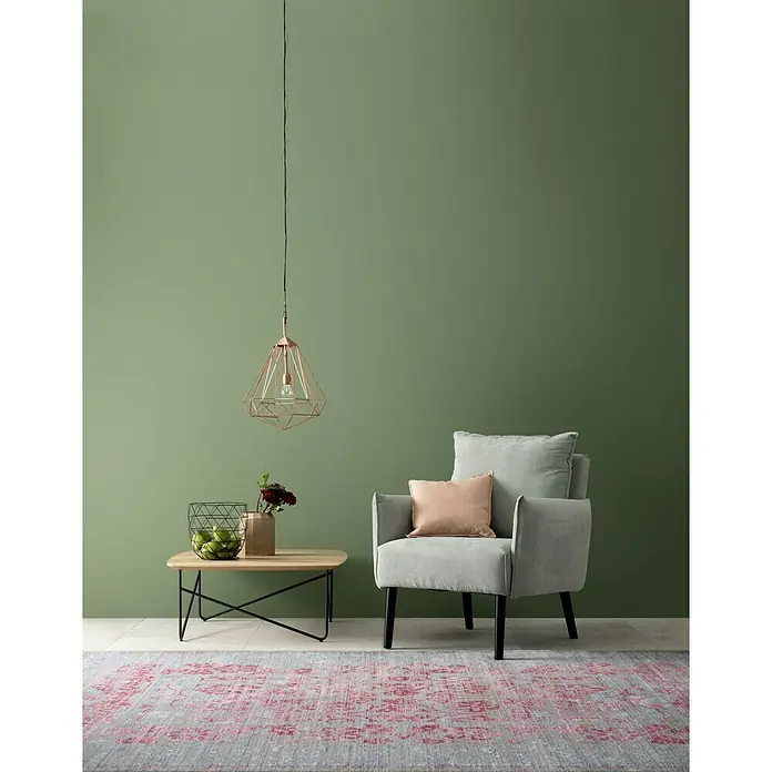 SCHÖNER WOHNEN-Farbe Wandfarbe Designfarbe - Ausgeglichenes Piniengrün, Matt, 2,5 l, Konservierungsmittelfrei - Eine stilvolle mintfarbene Sessellandschaft mit einem Couchtisch und einer modernen Kupferlampe vor einer grünen Wand.
