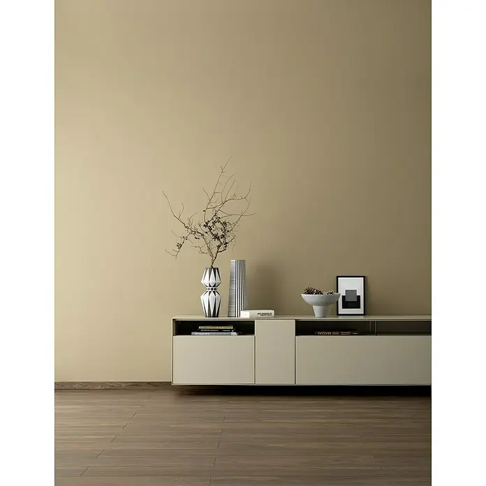 SCHÖNER WOHNEN-Farbe Wandfarbe Designfarbe - Warmes Erdbraun, Matt, 2,5 l, Konservierungsmittelfrei - Einrichtungsidee mit einem modernen Sideboard, dekoriert mit Vasen, Büchern und einer Schale, vor einer ockerfarbenen Wand.