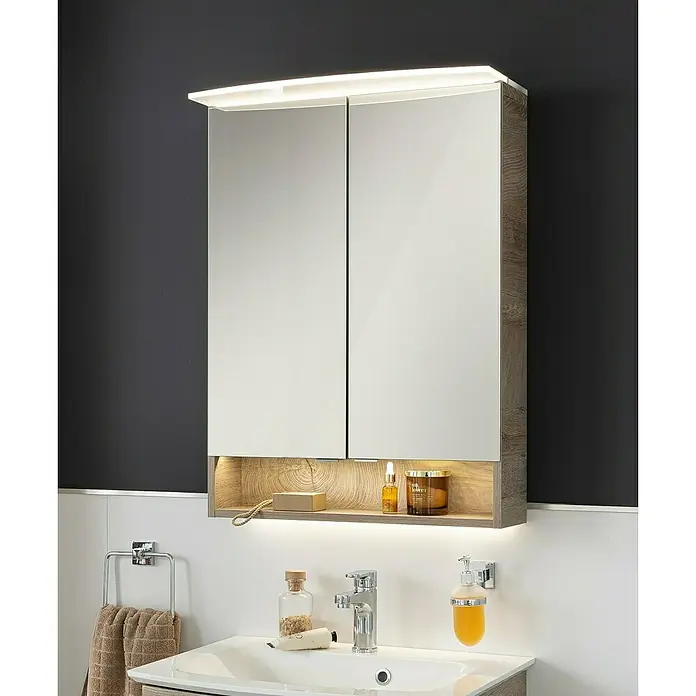 Fackelmann B.style LED-Spiegelschrank - B x H: 60 x 81,2 cm, Nature Oak Holzoptik - Ein beleuchteter Spiegelschrank mit zwei Türen, Holzrahmen und einem offenen Regal mit Pflegeprodukten, montiert über einem Waschbecken.