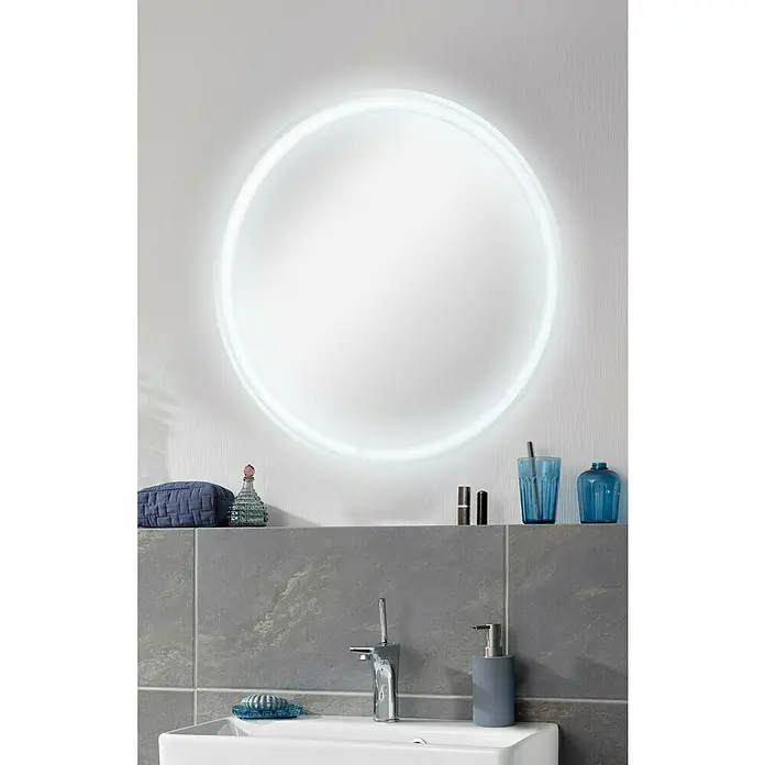 Fackelmann Lichtspiegel Mirror - Durchmesser: 60 cm, umlaufende LED-Beleuchtung - Ein runder Badezimmerspiegel mit LED-Beleuchtung und verschiedenen Badaccessoires auf einer grauen Ablage.
