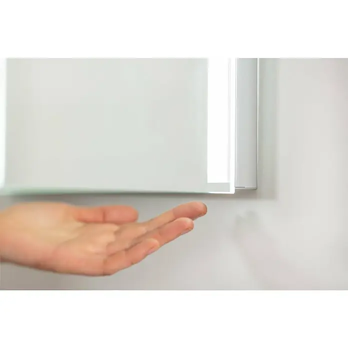 Fackelmann Mirrors LED-Lichtspiegel - B x H: 80 x 68 cm, Einfacher Anschluss über Schraubklemme, Rechteckig - Eine Hand nähert sich einem modernen Badezimmerspiegel mit integrierter Beleuchtung, der an einer weißen Wand hängt.