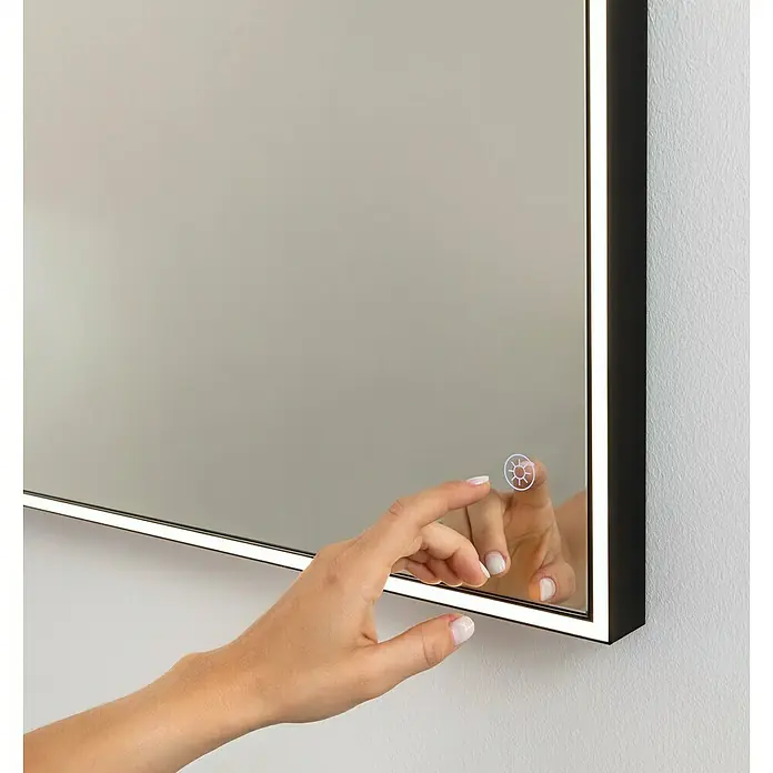 Fackelmann Mirrors LED-Lichtspiegel - 100 x 68 cm, Einfacher Anschluss über Schraubklemme, Rechteckig, Schwarz - Nahaufnahme eines beleuchteten Spiegels mit einer Hand, die den Touch-Button berührt, um die Helligkeit anzupassen. Elegantes Design für modernes Ambiente.