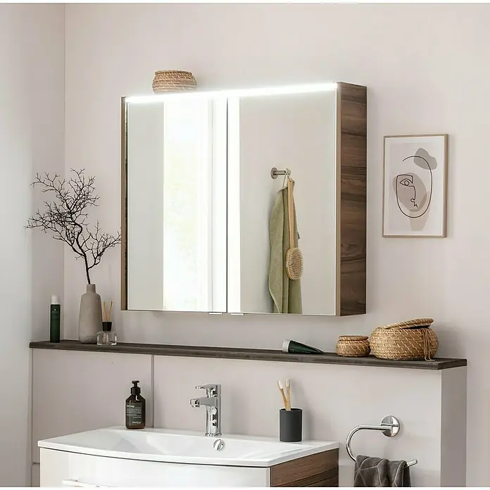 Fackelmann Verona LED-Spiegelschrank - 80 x 68,3 cm, Nussbaum Holzoptik - Badezimmer mit einem beleuchteten Spiegelschrank über einem Waschbecken mit Armaturen, Seife und Zahnputzbecher.