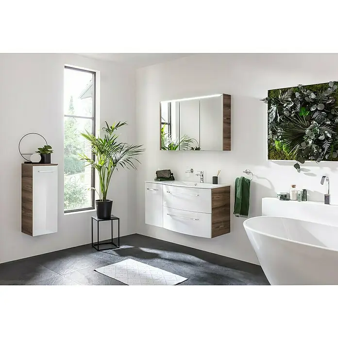 Fackelmann Verona Midischrank - B x T x H: 30,2 x 32 x 82,6 cm, DIN Anschlag: Links, Weiß Hochglanz/Nussbaum - Das Bild zeigt ein modernes Badezimmer mit einem weißen Waschtisch mit Holzstruktur, einem Spiegel und einer grünen Wanddekoration.