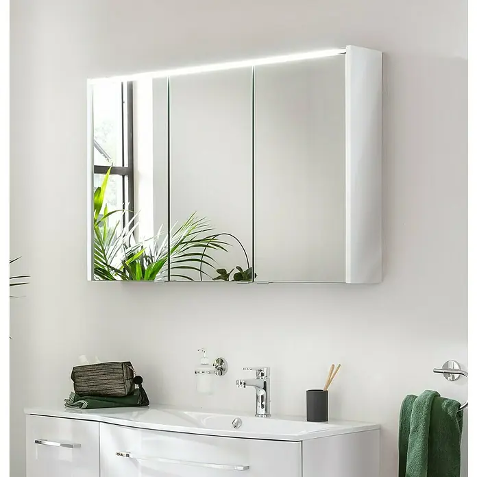 Fackelmann Verona Midischrank - B x T x H: 30,2 x 32 x 82,6 cm, DIN Anschlag: Links, Weiß Hochglanz/Nussbaum - Ein moderner Spiegelschrank mit integrierter Beleuchtung über einem stilvollen Waschbecken mit Armatur, Seifenspender und Handtuch.